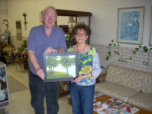 Doris Sexson, Fairfield Bay's local artist, presents Ricky Ridgway one of her paintings to be auctioned at the Crosseyed's silent auction on Saturday, April 5th from 3 to 7 p,m. The silent auction is open to the public and the proceeds go for college scholarships.