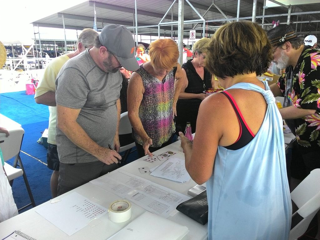 Shirley Rudolph reviews her hand as Past Commodore, Richard Mills and Secretary/Treasurer,, Nancy Mueller look on.