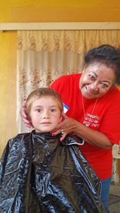 Mercie, one of the team members, cuts a childs hair prior to the start of school.