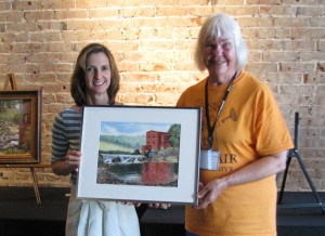 Tommie Fester of Steelville Drugs is shown presenting Joyce Hartmann with one of two purchase awards at the Steelville MO plein air competition. This watercolor was done on location at Dillard Mill. 